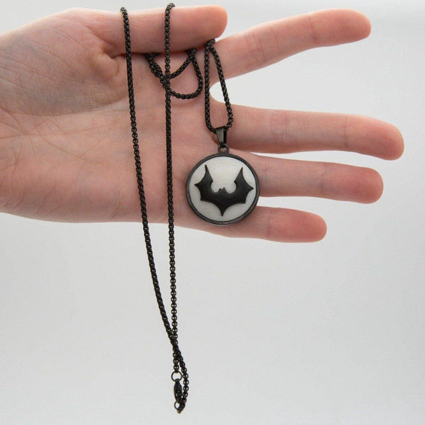 black metal cabochon with white logo demonstrated in hand