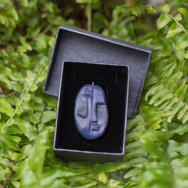 Dark blue two faced pendant in black gift box on green fern background