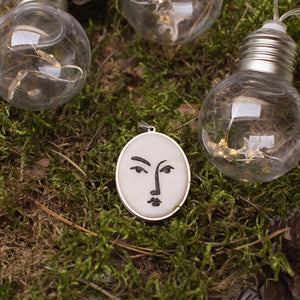 artistic white with black lines necklace in stainless steel cabochon laying in beautiful green moss