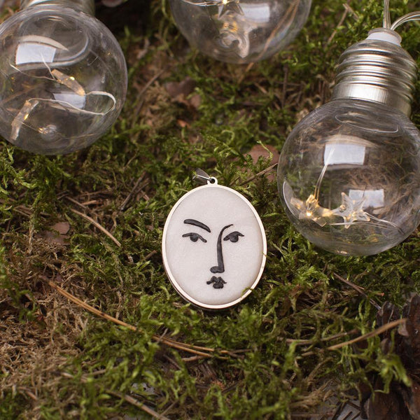 artistic white with black lines necklace in stainless steel cabochon laying in beautiful green moss