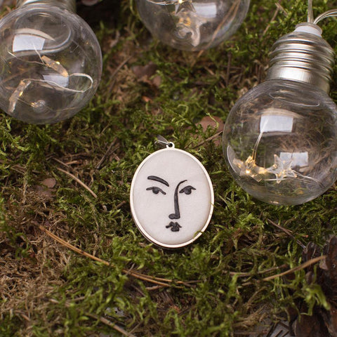 artistic white with black lines necklace in stainless steel cabochon laying in beautiful green moss