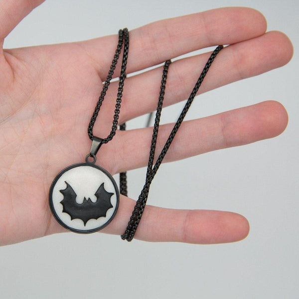 black metal cabochon with white logo demonstrated in hand