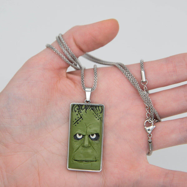 green frankenstein face in rectangular stainless steel cabochon demontrated in palm of the hand