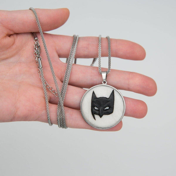 Metal cabochon with black batman mask in young woman's hand