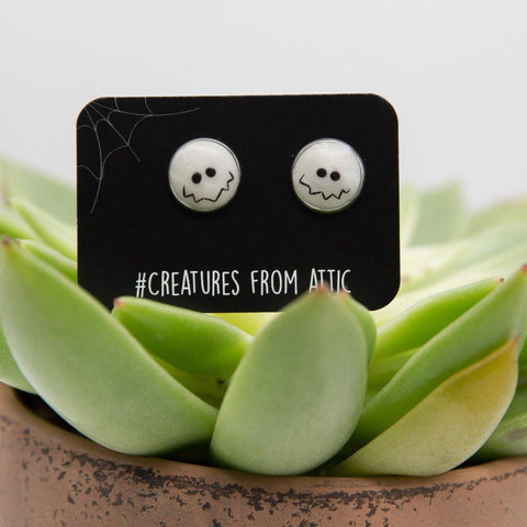 White hand-sculpted earrings with funny smile on black label named #creaturesfromattic