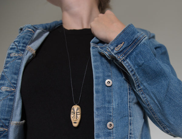 Cropped photo of girl demonstrating how face pendant looks like on black t-shirt and jeans jacket