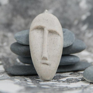 Tribal mask pendant made from stone imitation polymer clay in grey background 
