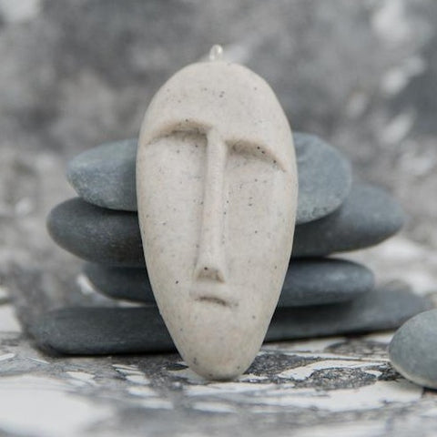 Tribal mask pendant made from stone imitation polymer clay in grey background 