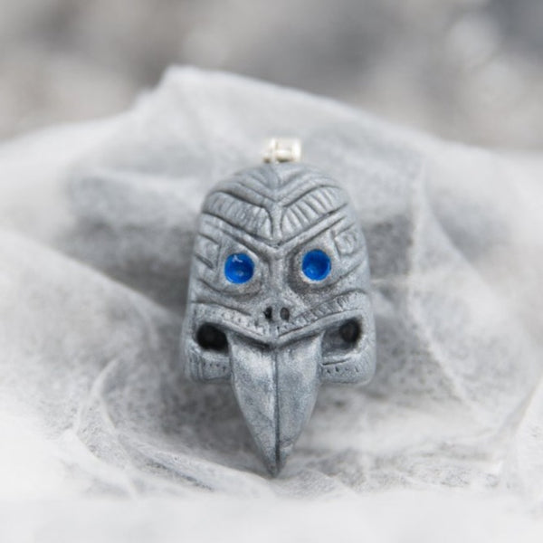 Maori tribal mask with sticking tongue pendant made from grey and blue polymer clay in white see-through background