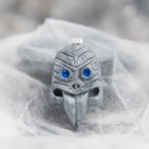 Maori tribal mask with sticking tongue pendant made from grey and blue polymer clay in white see-through background