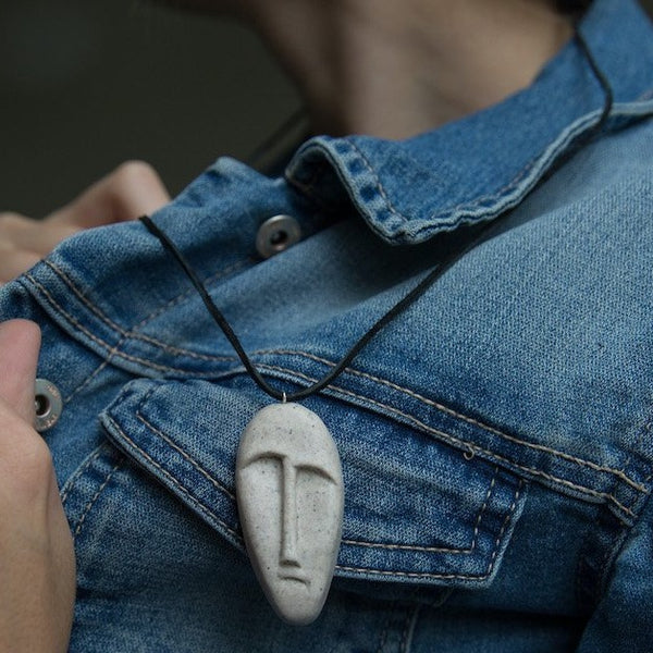 Stone mask pendant made from polymer clay demonstrated on blue jeans jacket