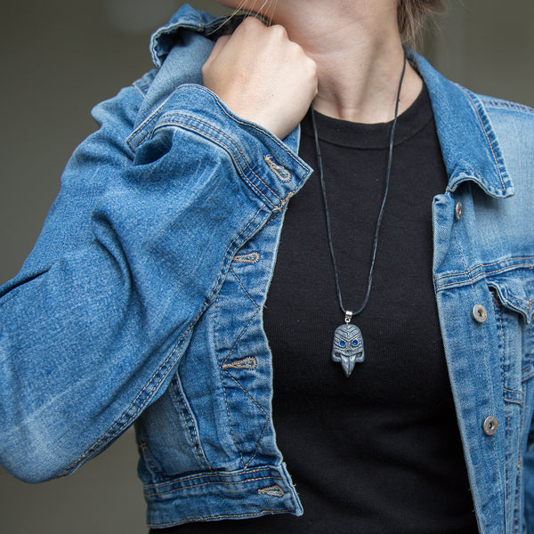 Grey maori tribal mask pendant demonstrated on girl wearing black shirt and blue jeans jacket