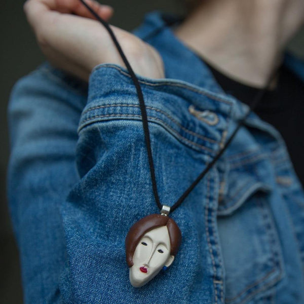 Cropped photo of girl demonstrating how face pendant looks like on blue jeans jacket